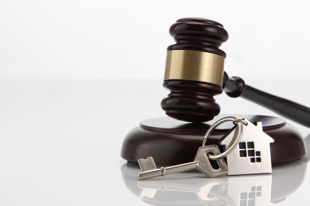 Gavel with a house-shaped keychain and key, symbolizing real estate law, property auctions, or legal decisions in housing